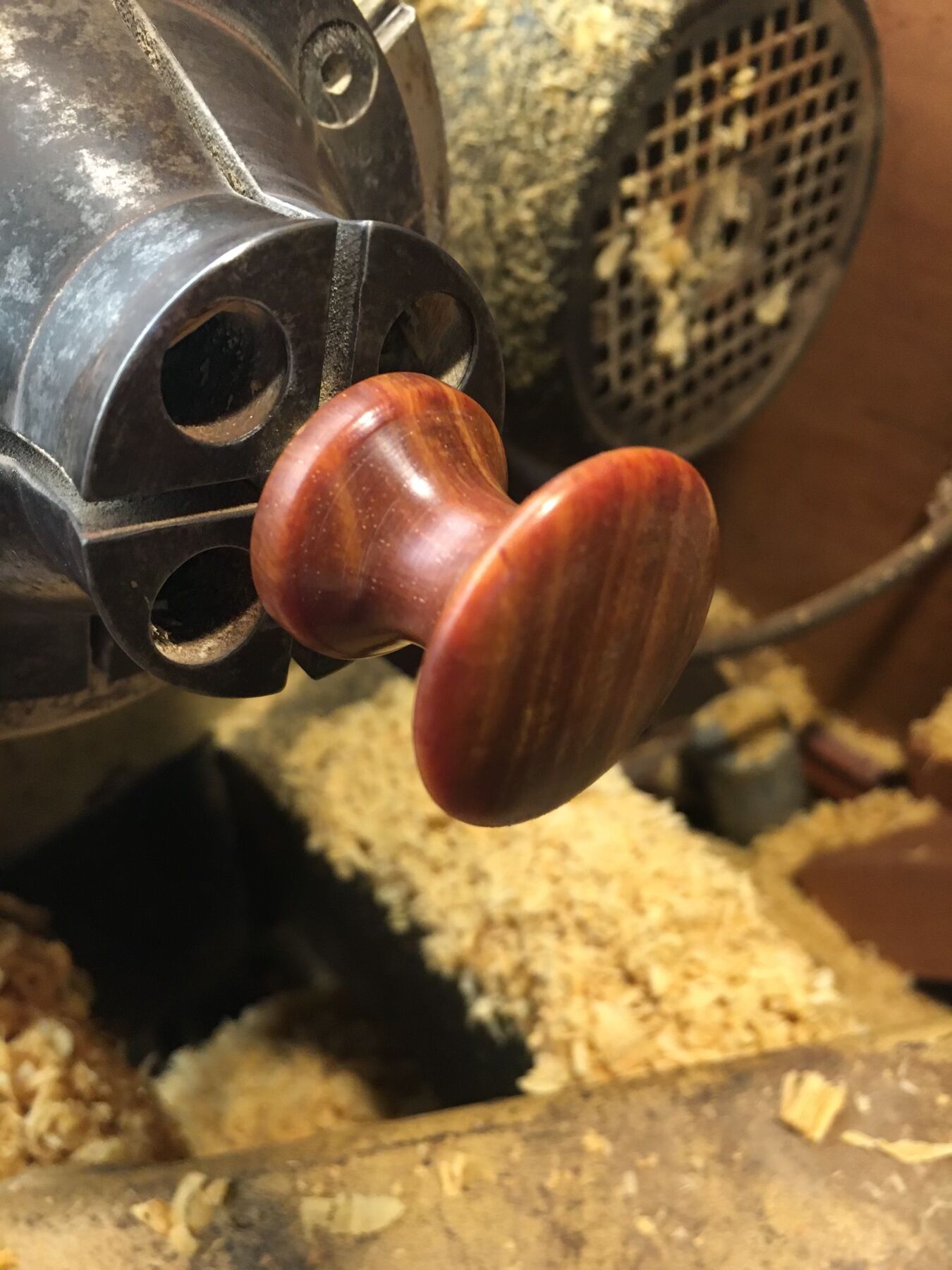 A hand-turned wooden knob on the lathe