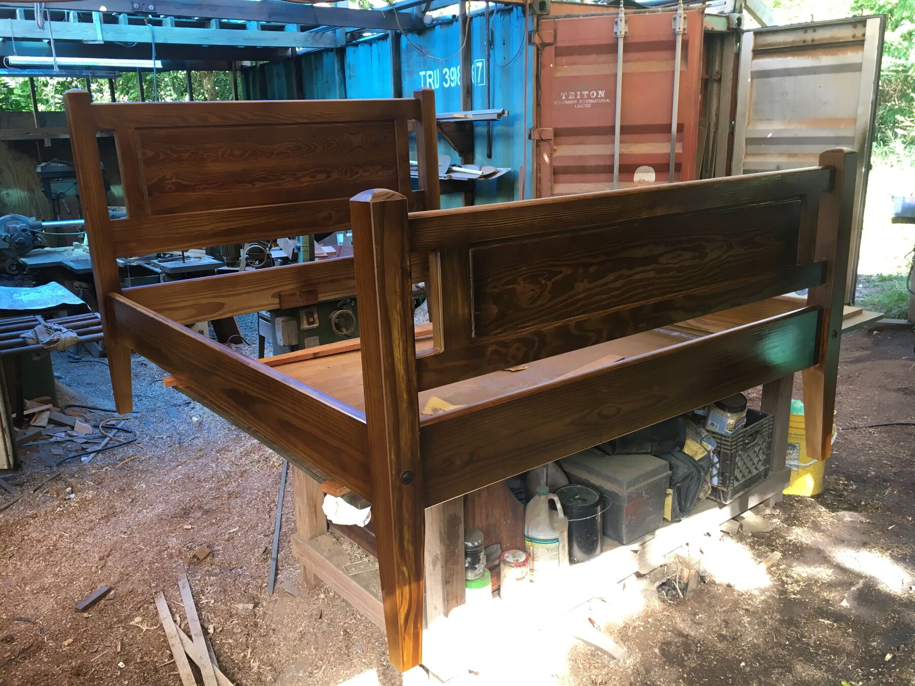 A bed frame in progress between the shipping containers of the Coral Bay shop